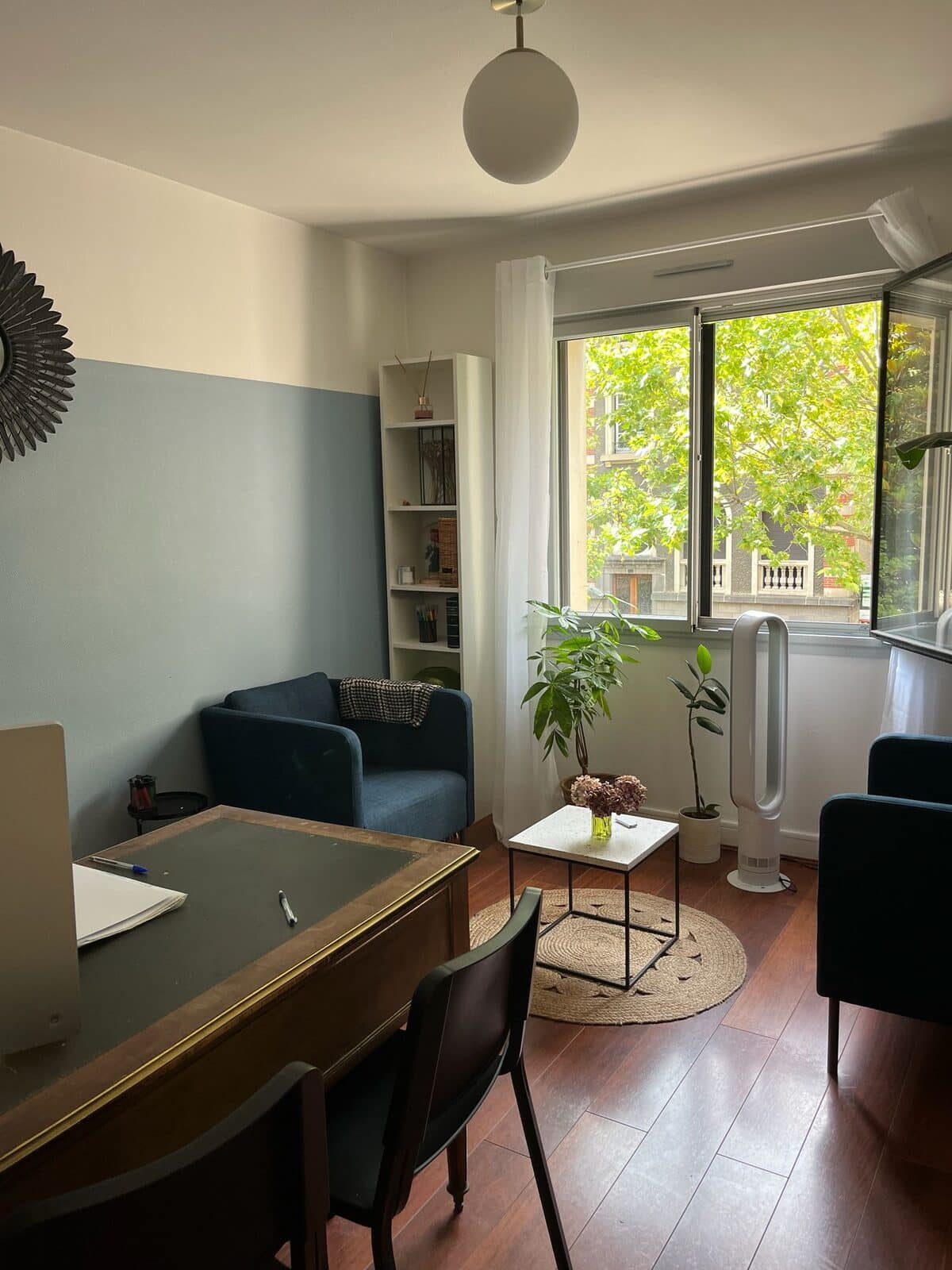 Le cabinet de consultation : bureau, fauteuil bleu et grande fenêtre
